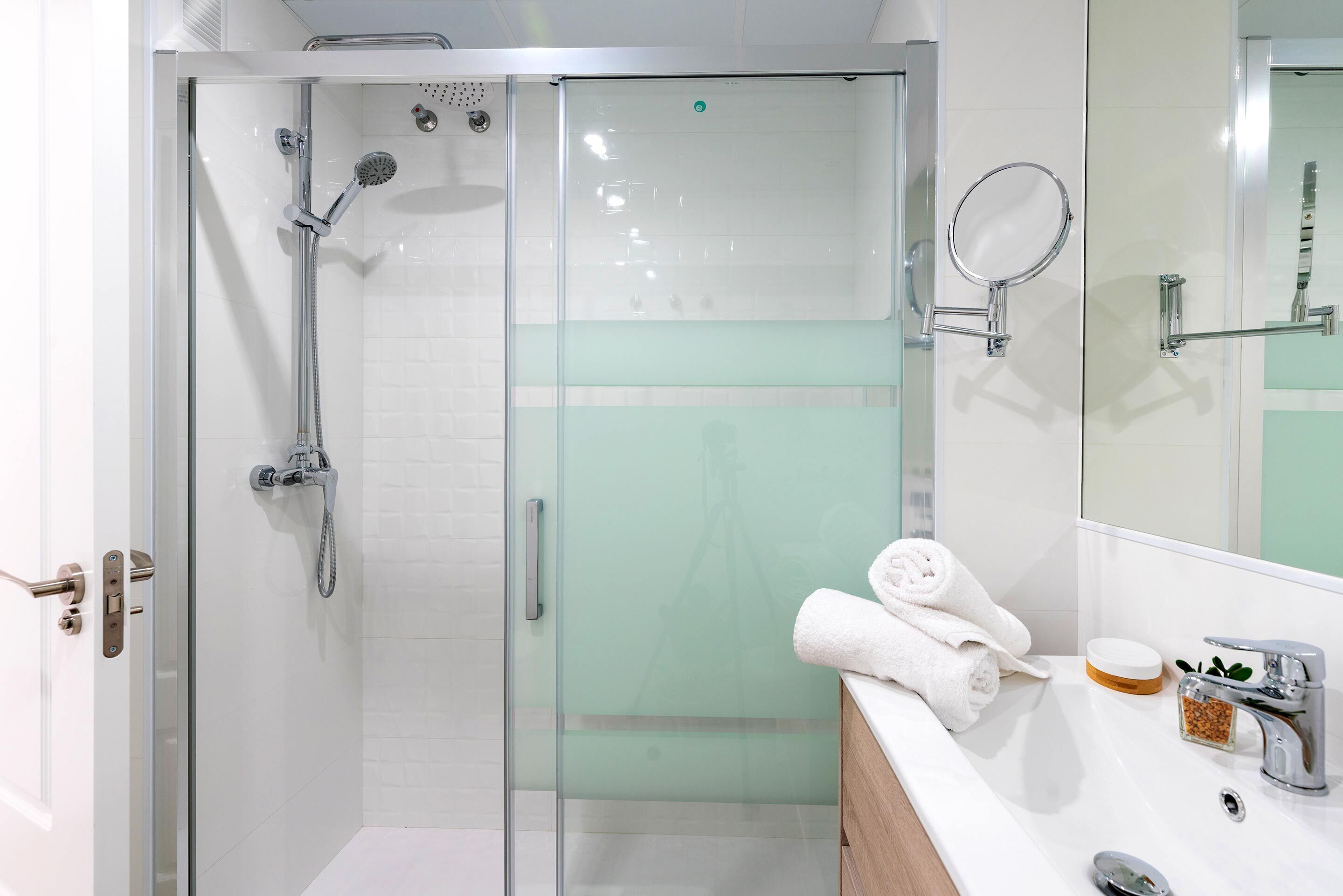 A modern bathroom with a glass-enclosed shower, a vanity with a mirror, and a sink with a soap dish.