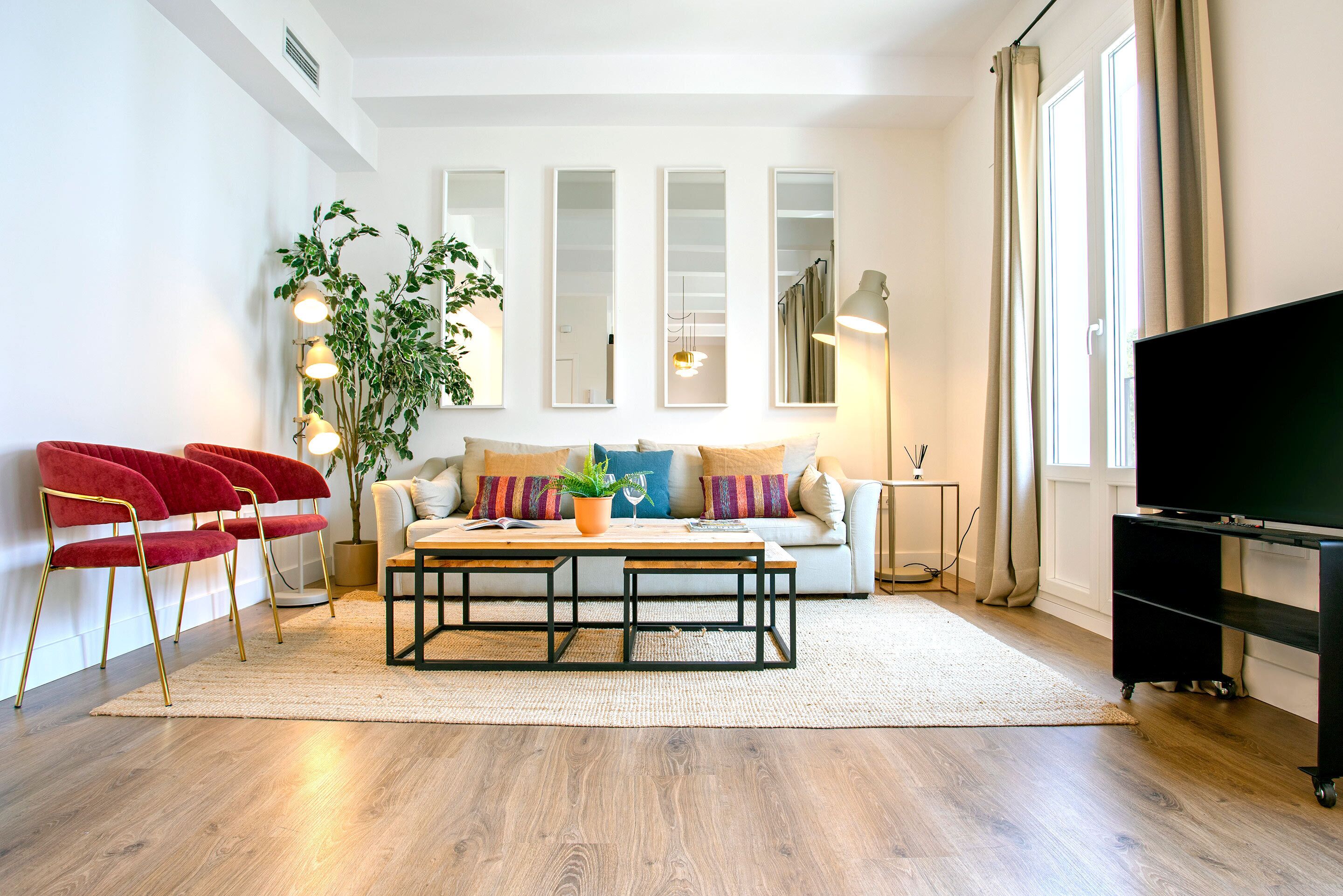 A modern living room with a sofa, red chairs, a coffee table, and a TV.