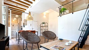 Ein moderner Wohnraum mit Esstisch aus Holz, Korbstühlen, einer Zeitschrift und einer Treppe.