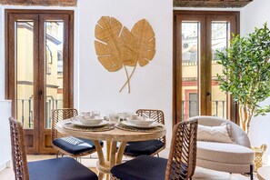 A dining area with a round table, chairs, and a large decorative leaf on the wall. - Genteel Home Santas Patronas (Seville)