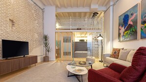 A modern living room with a flat-screen TV, a red armchair, a coffee table, and a bookshelf. - Genteel Home Santas Patronas (Seville)