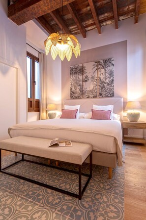 A bedroom with a bed, bedside tables, a hanging light fixture, and a wall mural. - Genteel Home Santas Patronas (Seville)