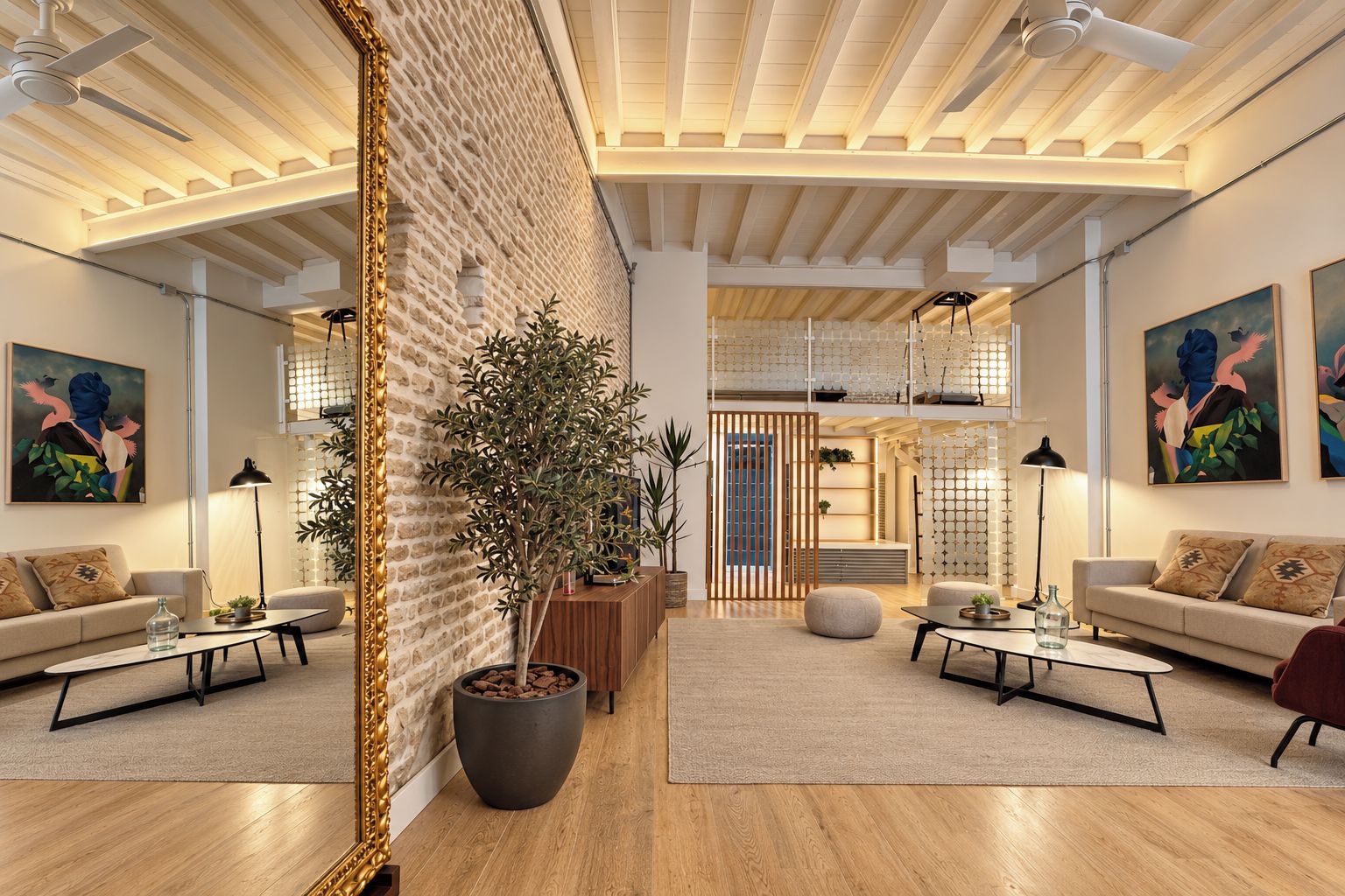 Un interior moderno con techo alto, paredes de ladrillo visto y un área de estar central con sofás y una mesa de centro.
