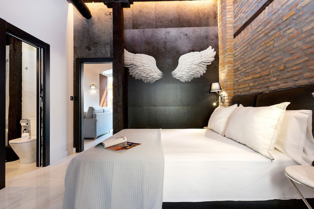Ein modernes Hotelzimmer mit einem großen Bett, einer Ziegelwand und einer einzigartigen, flügelartigen Dekoration.