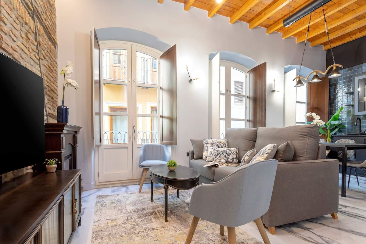 A modern living room with a sofa, armchairs, a coffee table, and a TV.