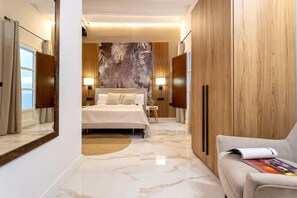 Une chambre d’hôtel moderne avec un grand lit, une armoire en bois et un coin salon avec un magazine.