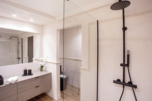 A modern bathroom with a glass shower enclosure, a vanity with a mirror, and a toilet. - Genteel Home Incosol (Marbella)