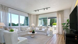 Ein modernes Wohnzimmer mit einer Sofagarnitur, einem Couchtisch und einem Fernseher.