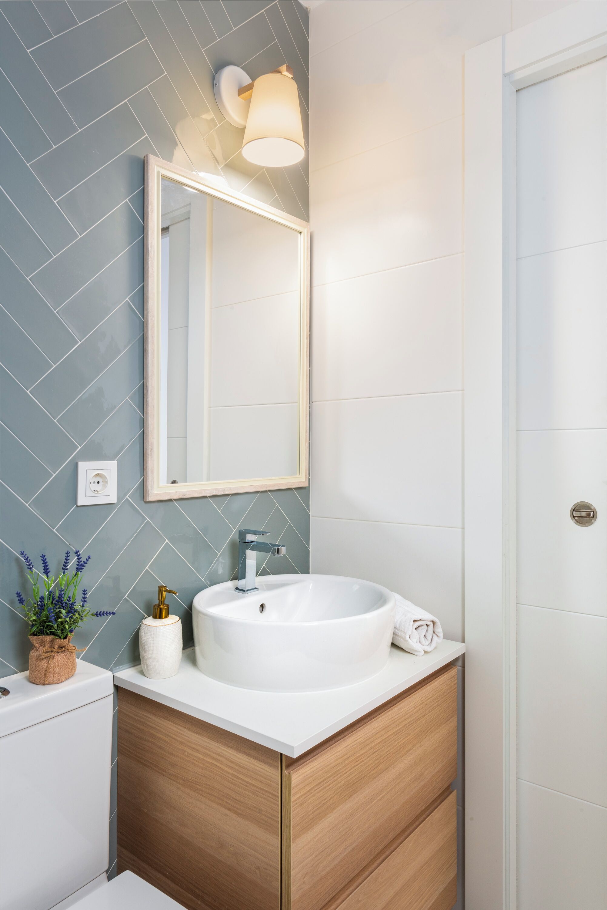 A modern bathroom with a white sink, wooden vanity, and a large mirror.