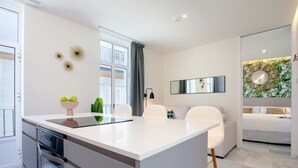 Una cucina moderna con isola centrale, mobili bianchi e zona pranzo con sedie bianche.