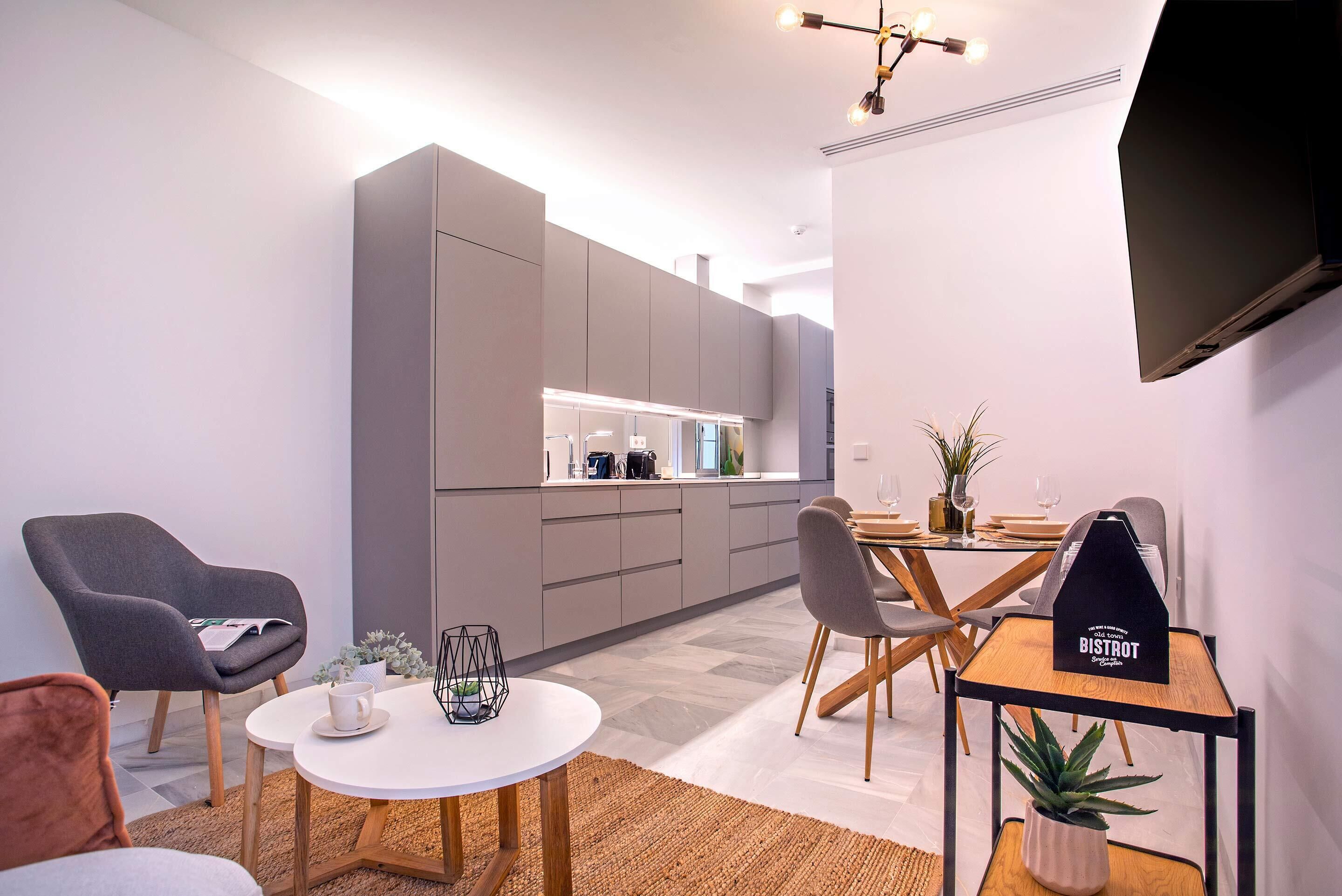 A modern living room with a dining area, grey cabinets, a flat-screen TV, and a sign for 'BISTROT'.