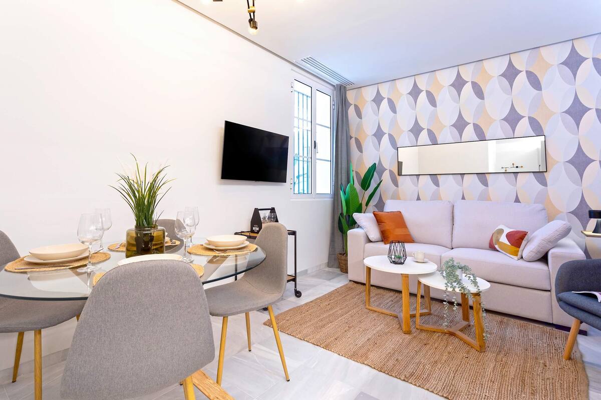 Un salon moderne comprenant un coin repas, un canapé, un téléviseur et une grande fenêtre.