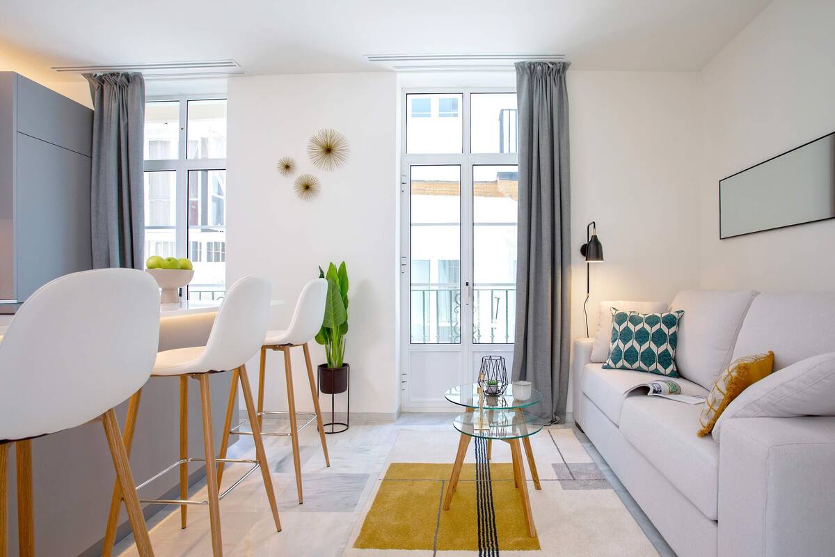 Un salon moderne avec un canapé, une table basse en verre et un coin repas comprenant des chaises et une petite table.