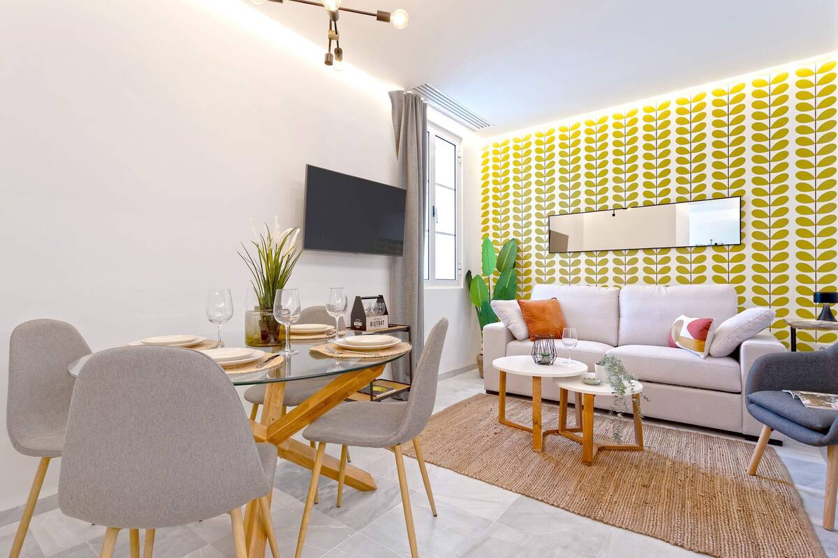 Un salon moderne comprenant un coin repas, un canapé et un téléviseur fixé au mur.