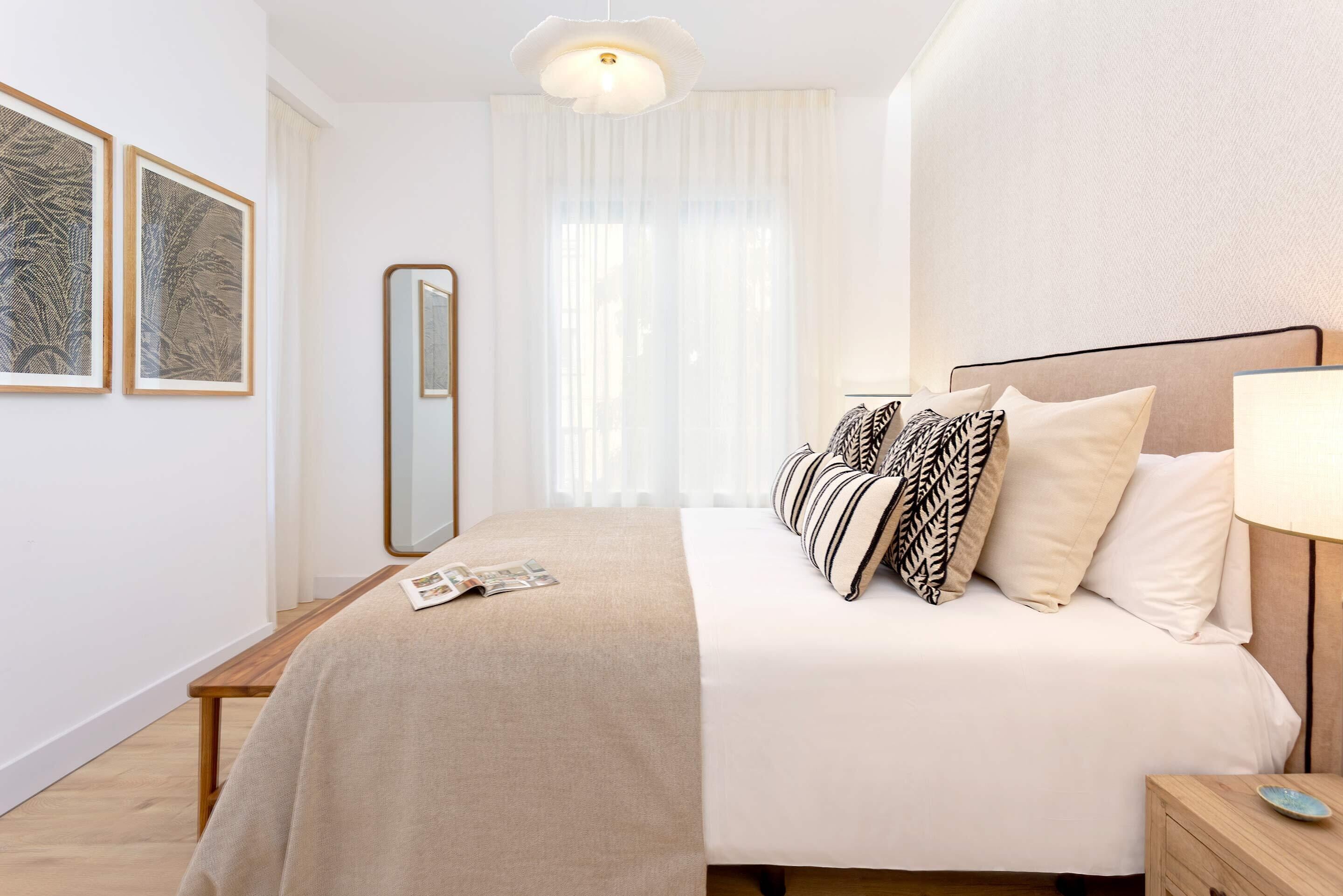 A neatly arranged bedroom with a bed, bedside table, and a mirror.