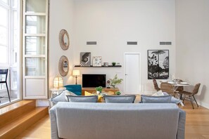 A modern living room with a grey sofa, a TV, and a dining area with wicker chairs. - Genteel Home San Agustín (Málaga)