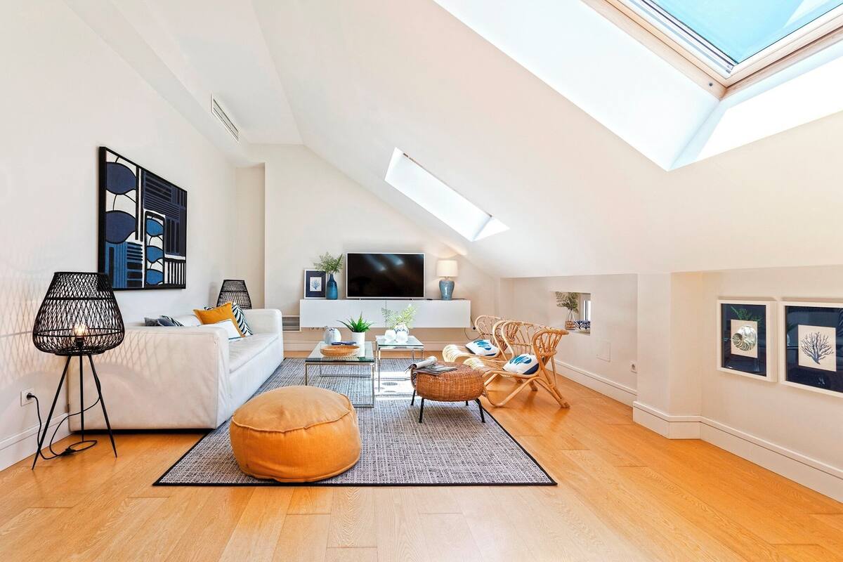 A modern living room with a white sofa, a coffee table, and a large window.