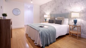 A bedroom with a bed, bedside tables, a mirror, and a door. - Genteel Home San Agustín (Málaga)
