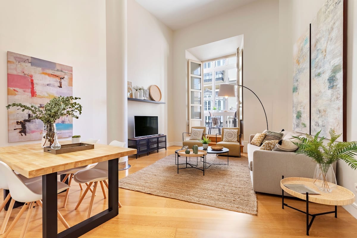 A modern living room with a wooden dining table, a sofa, and a TV.