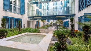 A modern building with a courtyard featuring a water feature and lush greenery. - Genteel Home San Agustín (Málaga)