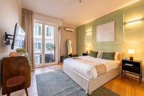 Une chambre d’hôtel avec un grand lit, un bureau, une chaise, un balcon avec vue et une œuvre d’art accrochée au mur.