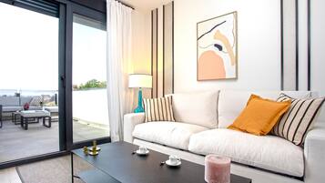 A modern living room with a sofa, a coffee table, and a view through a glass door.