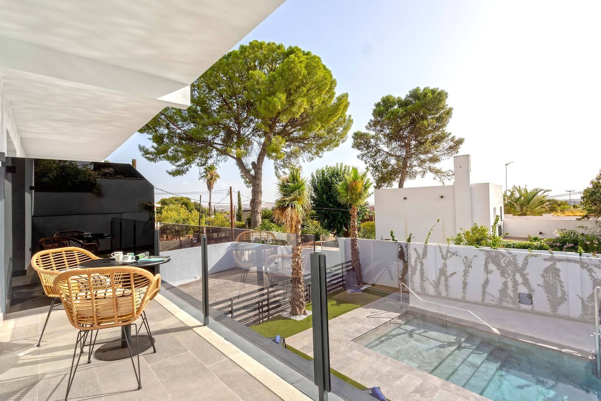 Un patio al aire libre con piscina, sillas de mimbre y una mesa.