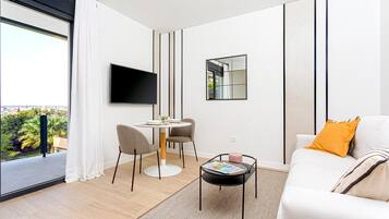 Una sala de estar moderna con sofá, mesa de centro, televisor y comedor con sillas y mesa.