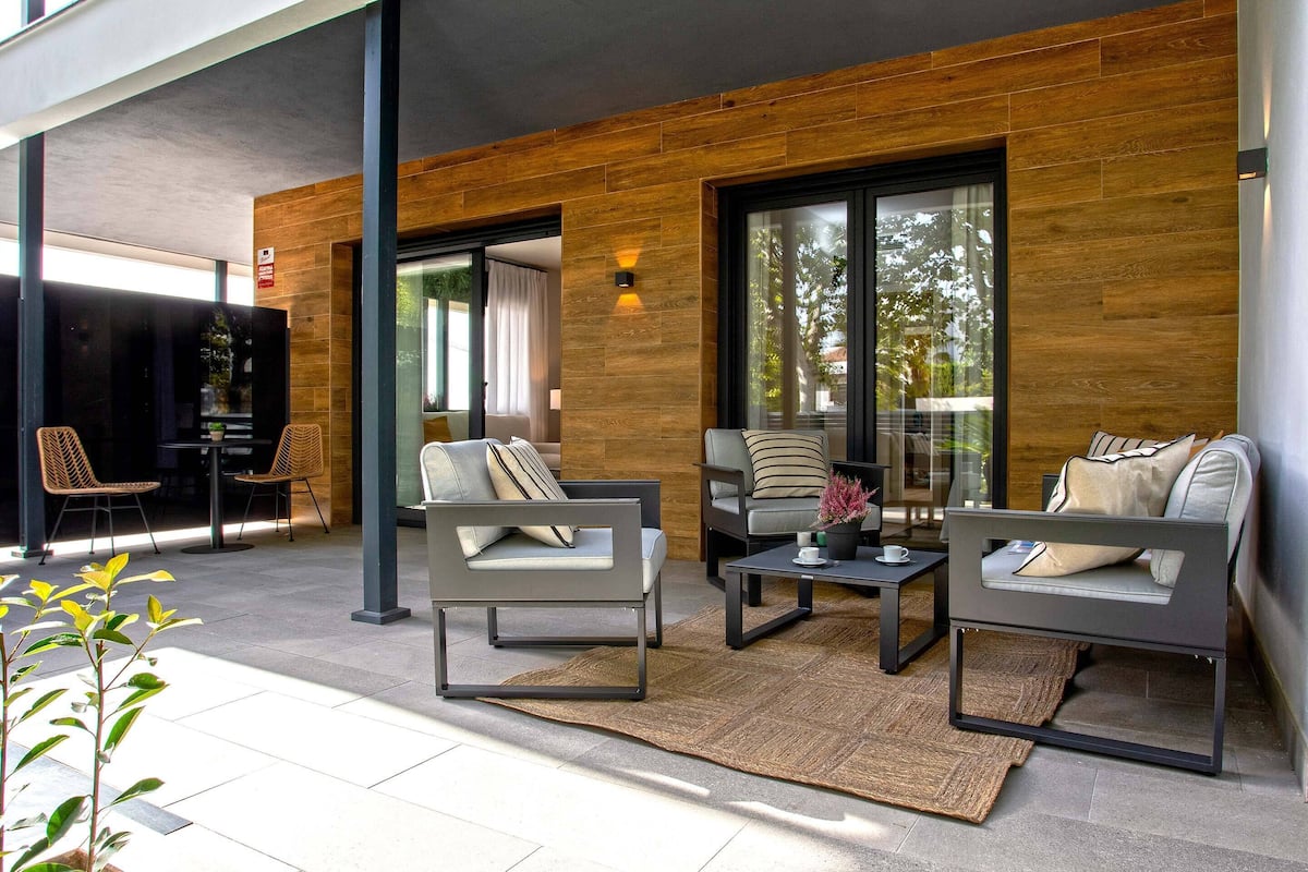 Un área de estar exterior moderna con dos sofás y sillones, una mesita de centro y una alfombra.
