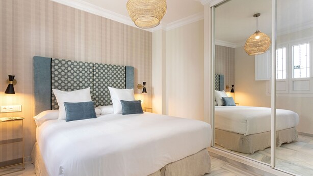 A bedroom with a large bed, a mirror, and two bedside lamps. - Genteel Home San Isidoro (Seville)
