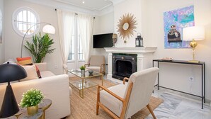 A living room with a fireplace, a television, and a painting on the wall. - Genteel Home San Isidoro (Seville)
