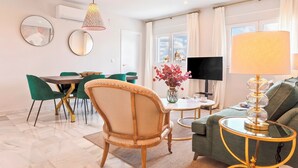 Ein modernes Wohnzimmer mit Essbereich, einer Couch, einem Fernseher und einer Lampe.