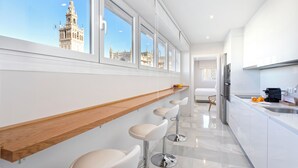 Eine moderne Küche mit einer langen Theke, Barhocker und Blick auf ein historisches Gebäude.