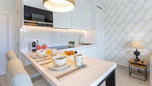 A modern kitchen with white cabinetry, a hanging light fixture, and breakfast items on the counter. - Genteel Home Ricardo Soriano Terrace (Marbella)