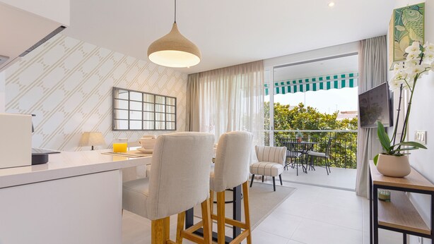 A modern kitchen with a dining area, a balcony with a view, and a TV on the wall. - Genteel Home Ricardo Soriano Terrace (Marbella)