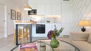 A modern kitchen with white cabinets, a built-in oven, and a dining area with stools. - Genteel Home Ricardo Soriano Terrace (Marbella)