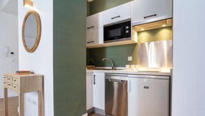 Cocina compacta con armarios blancos, lavavajillas Bosch, microondas y una mesita de madera con un libro.