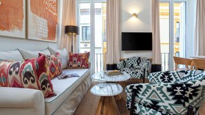 Una sala de estar moderna con un sofá, sillones, una mesa de centro y un televisor de pantalla plana.