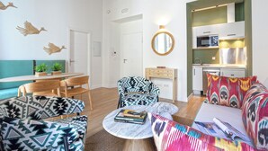 Una sala de estar moderna con muebles estampados, un comedor y una cocina con electrodomésticos integrados.