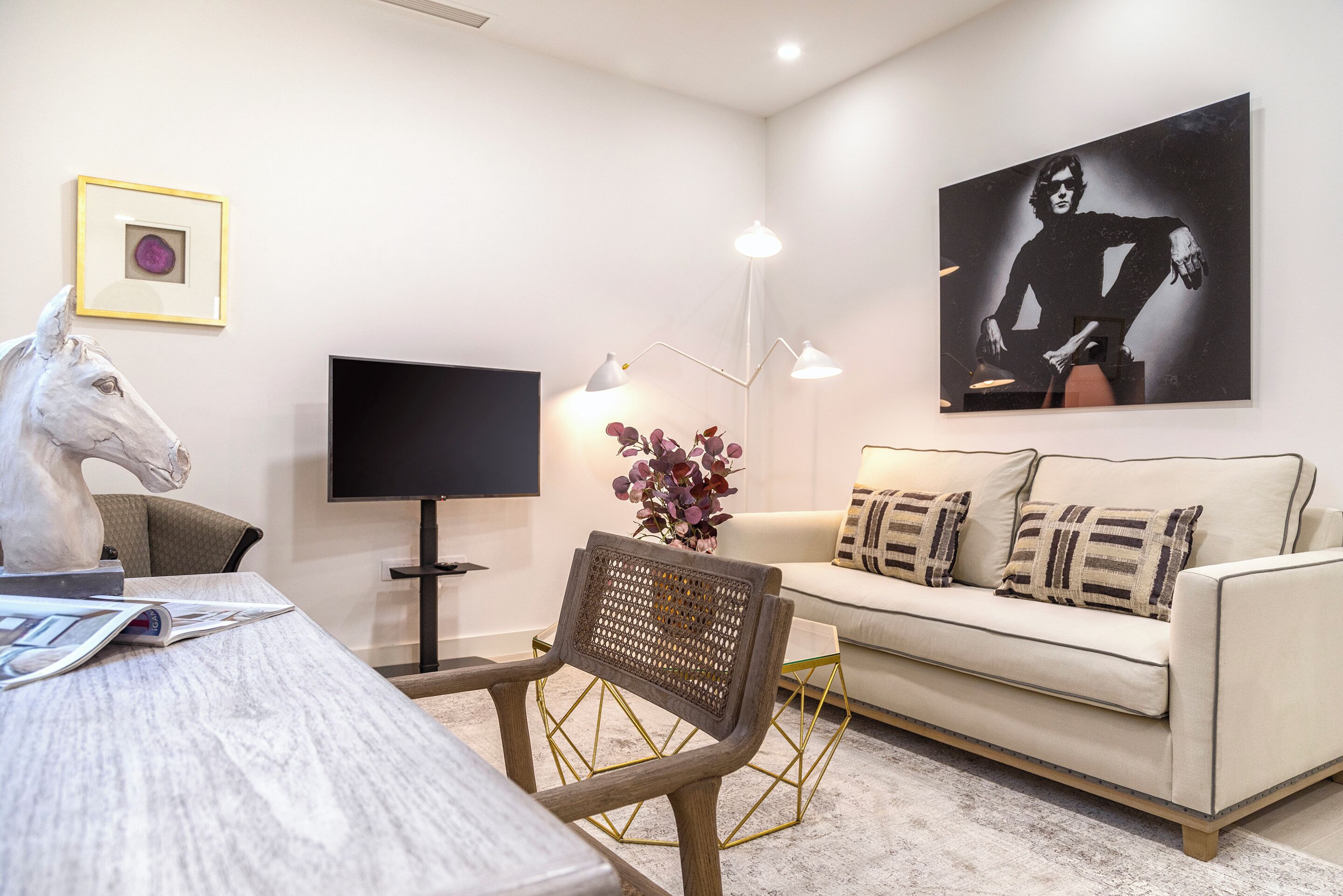 A modern living room with a sofa, a coffee table, a TV, and artwork on the wall.