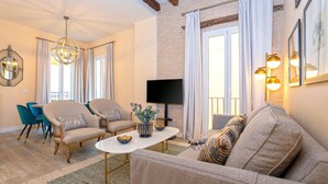 A living room with a sofa, armchairs, a coffee table, and a TV. - Genteel Home Feria (Seville)