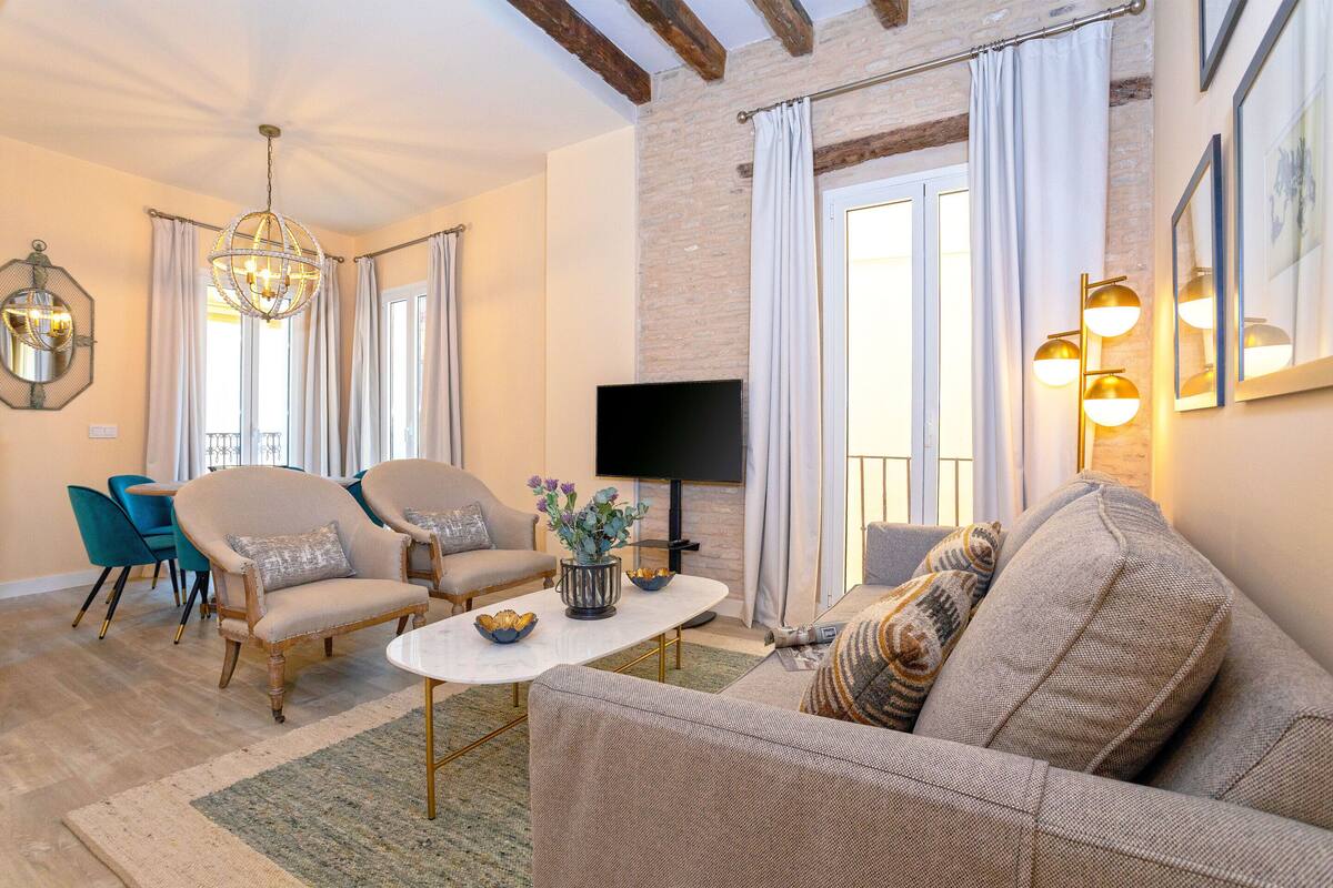 A living room with a sofa, armchairs, a coffee table, and a TV.