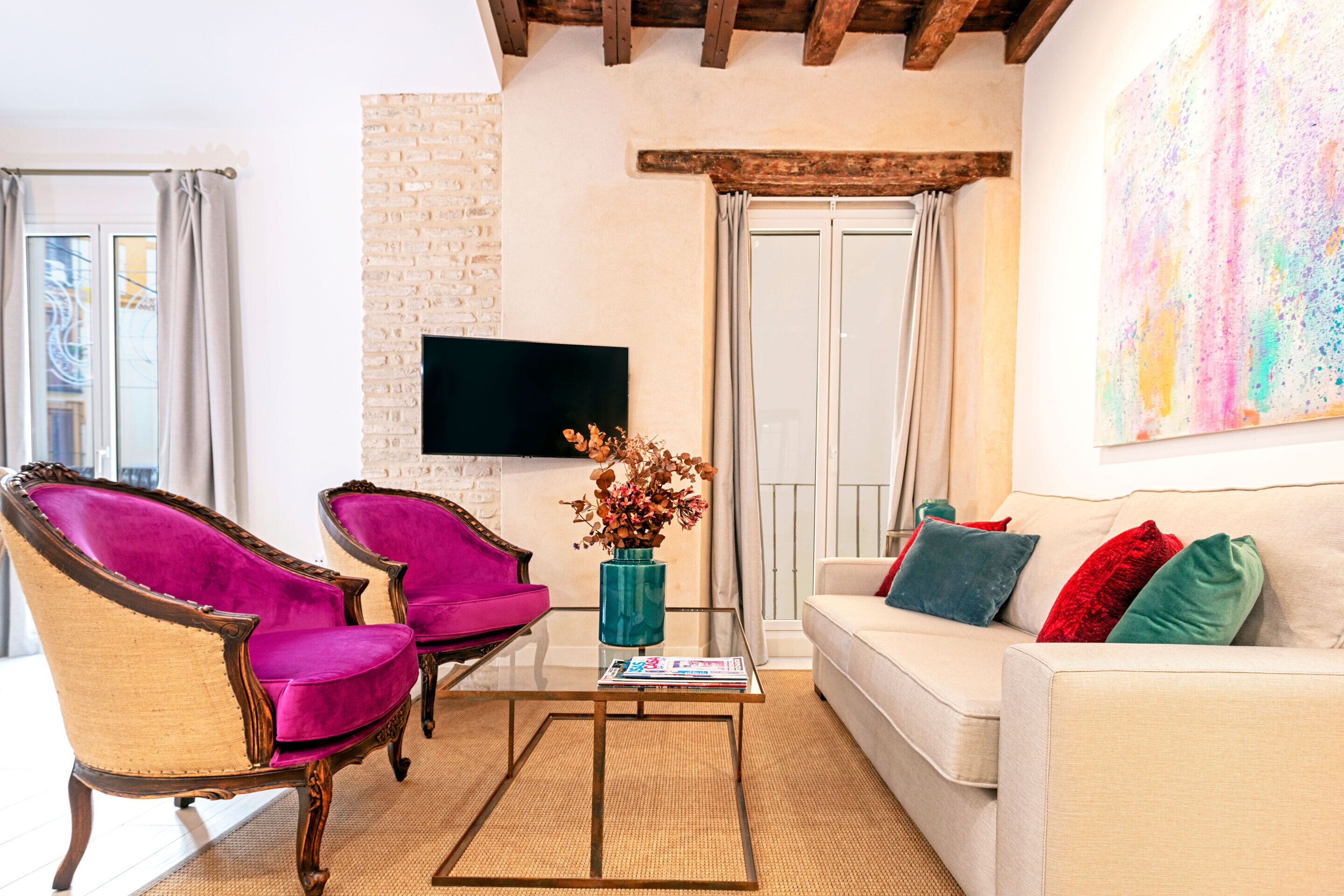 A living room with a white sofa, two armchairs, a coffee table, a flat-screen TV, and a fireplace.
