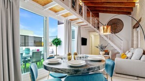 A dining area with a round table, blue chairs, and a view of the outdoors. - Genteel Home Feria (Seville)