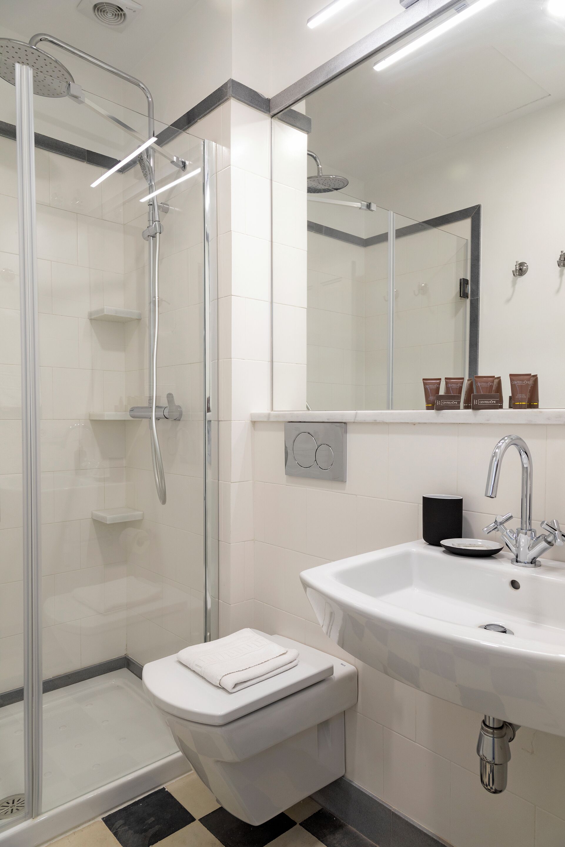 A modern bathroom with a glass-enclosed shower, a white sink, and a toilet.