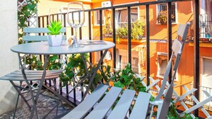 Un balcon avec une table, des chaises et un pot de fleurs.