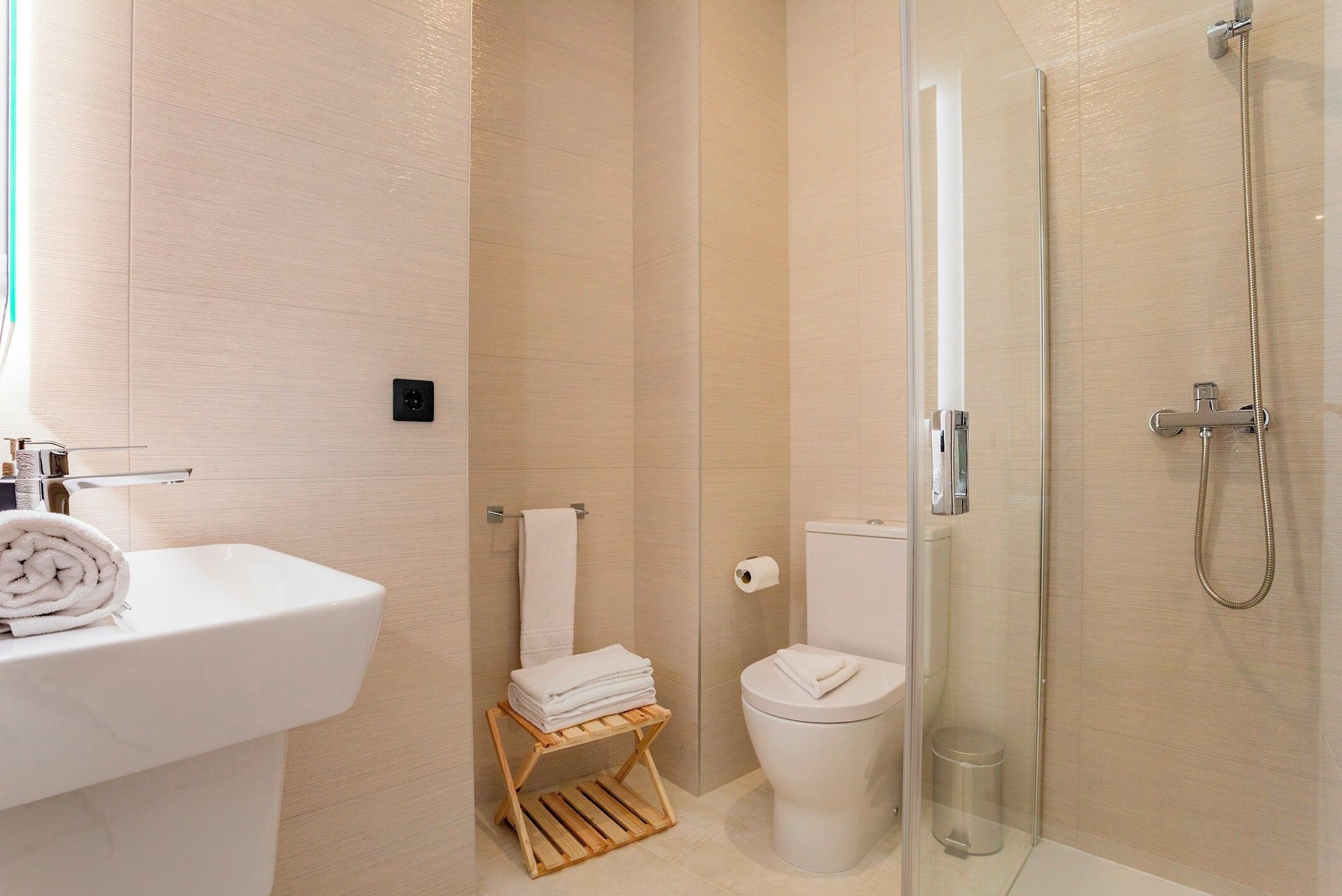 A modern bathroom with a white sink, toilet, and glass-enclosed shower.