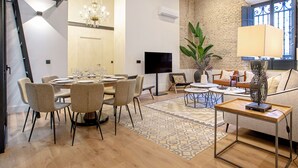 A spacious living area with a dining table set for six, a sofa, a coffee table, and a TV. - Genteel Home Almansa (Seville)