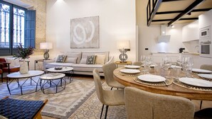 A modern living room with a sofa, coffee table, and dining area set up for a meal. - Genteel Home Almansa (Seville)