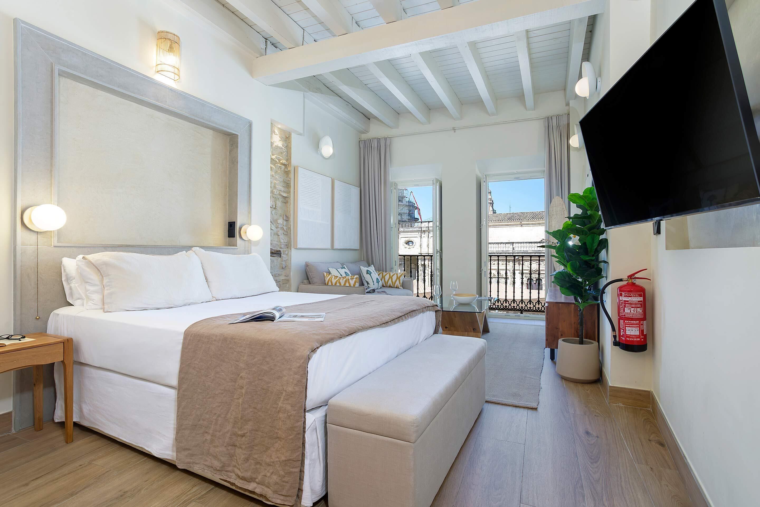 A modern hotel room with a large bed, bedside table, and a flat-screen TV.